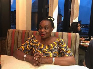 Woman sitting at a restaurant table, smiling and relaxed.