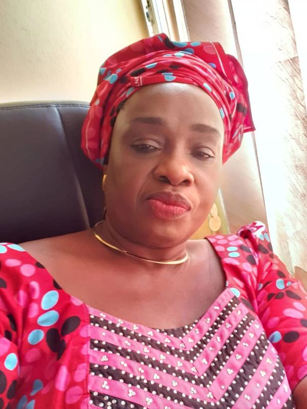 Woman in vibrant traditional attire with a red headwrap and necklace.