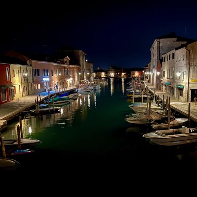 A night shot of boats along a canal in the city of Murano Venice, Italy. 