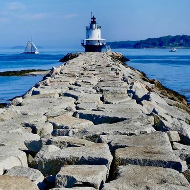 A short lighthouse at the end of a stone pathway. 