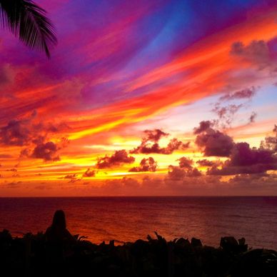 A women on a bench studies a beautify sunset with mixtures of blue, pink, red and orange.