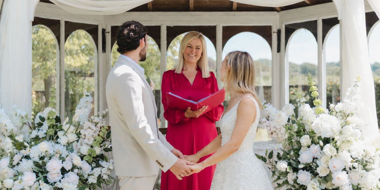 Couple holding hands during wedding ceremony with officiant.