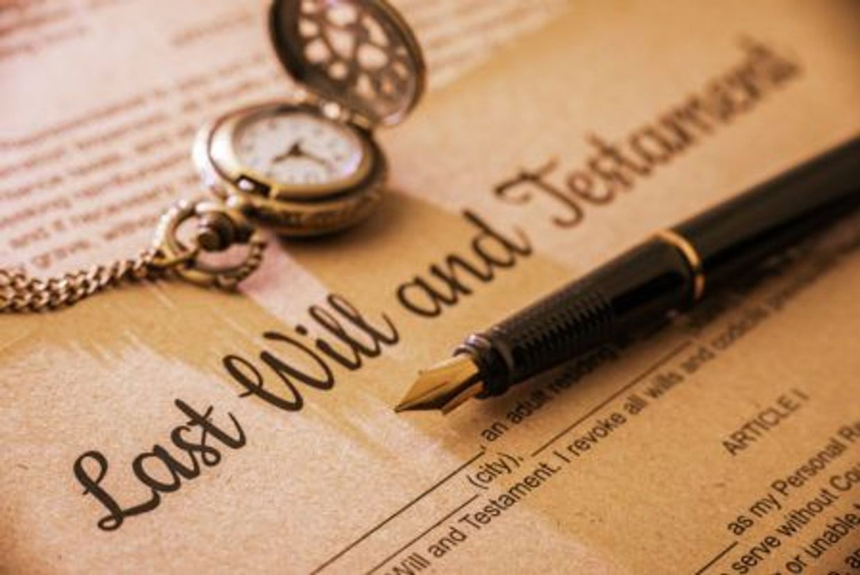 A vintage pocket watch and a fountain pen on a last will and testament document.