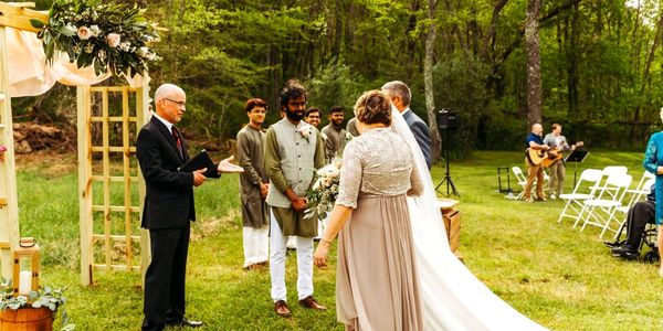 Outdoor wedding ceremony with couple and officiant.