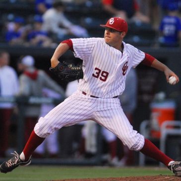 Baseball player in white pinstriped uniform pitching on the mound.