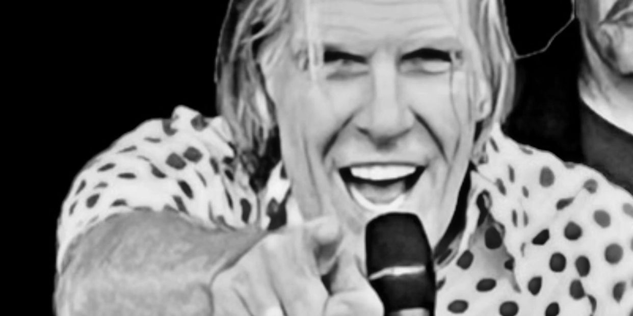 Man with a microphone pointing and smiling.