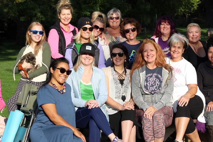 A group of women smiling together outdoors on a sunny day.