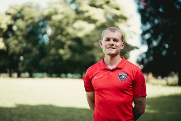 Young man in a red sports shirt outdoors.