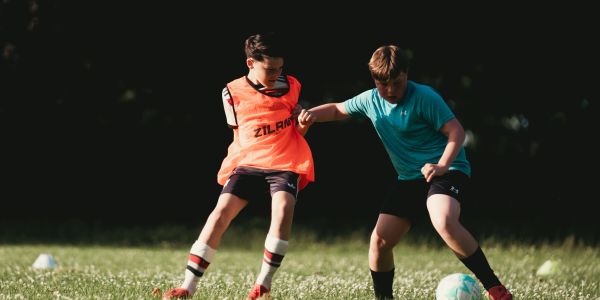 Two boys playing soccer with focused expressions.