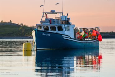 Fishing boat anchored on calm water during sunset.