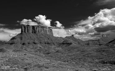 Black and white photo of a desert mesa under a cloudy sky.