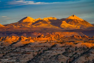 Sunset illuminates a rugged mountain range with golden light.