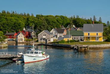 Fishing boat near colorful coastal houses.
