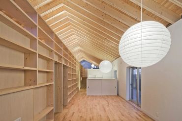 Minimalist wooden room with high ceiling and round paper lanterns.