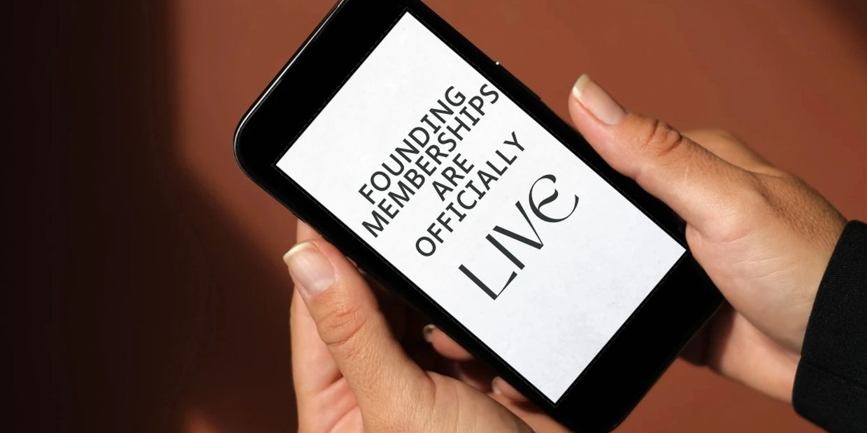 Person holds phone displaying 'Founding Memberships Are Officially Live' message.