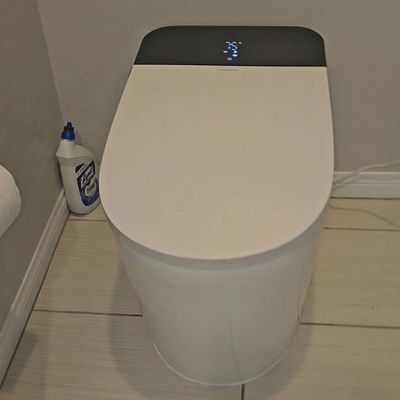Modern white smart toilet with digital controls on the lid.