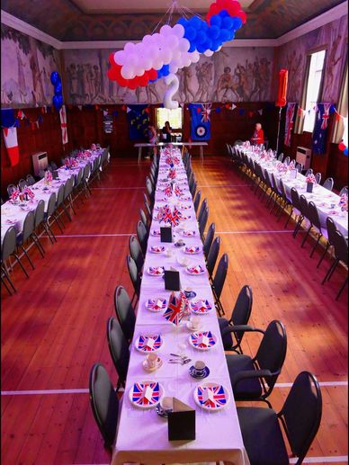 A room decorated for a British-themed party with long tables and Union Jack plates.