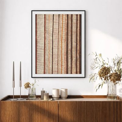 Modern framed abstract art with vertical lines above wooden sideboard.