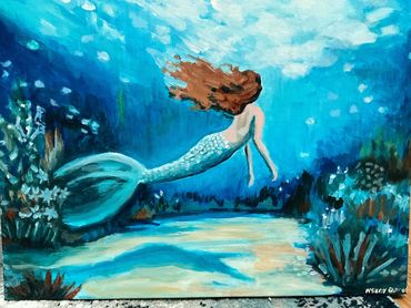 Mermaid in blues and greens swimming in the water.