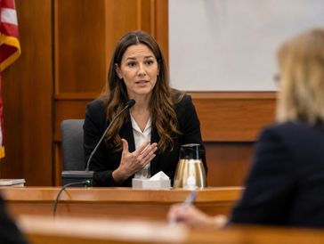 A woman testifies in a courtroom setting during a legal proceeding.