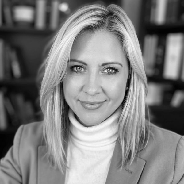 Professional headshot of a confident woman with blonde hair and a blazer.