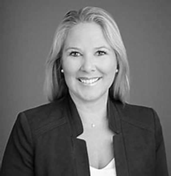 Black and white portrait of a smiling woman in professional attire.