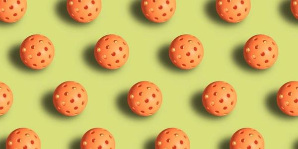 Orange perforated balls arranged in a grid on a green surface.