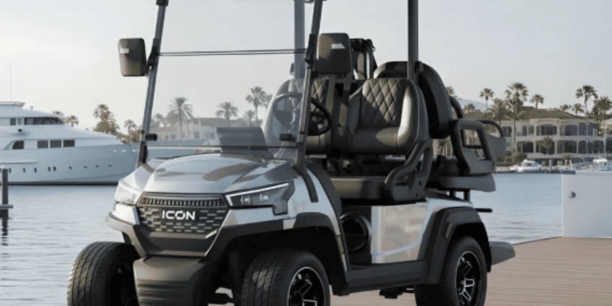 New ICON electric golf cart in silver with diamond-stitched black seats and black wheels parked at m