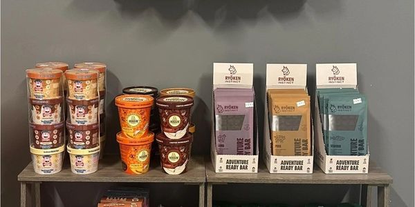 Variety of snack bars and ice cream tubs displayed on wooden shelves.