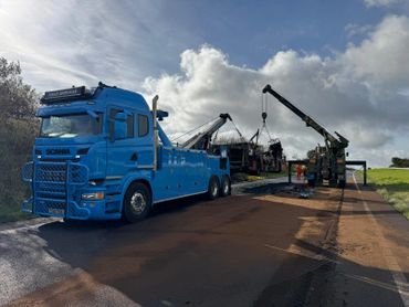 Blue heavy-duty tow truck assisting at a roadside incident with cranes.