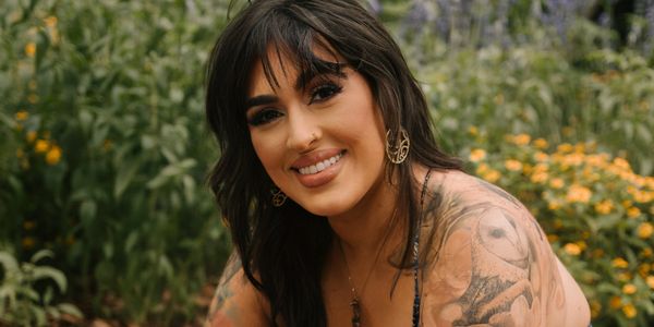 Woman sitting on rug on ground surrounded by flowers