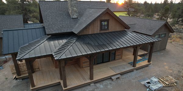 A wooden cabin with a metal roof under construction in a rural area.