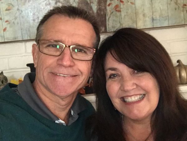 Smiling couple posing closely indoors with autumn-themed decor in the background.