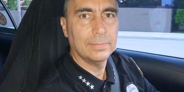 Security officer in uniform sitting inside a vehicle wearing a seatbelt.