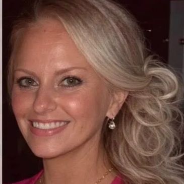 Smiling woman with blonde hair styled in loose waves and elegant earrings.