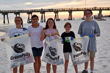 kids pose with GreenPolly bags during a beach clean-up