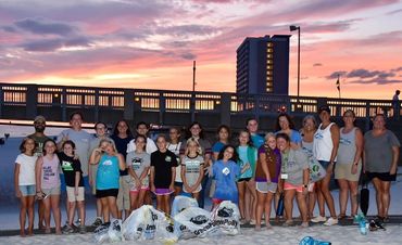 Volunteers with GreenPolly bags at sunset after a beach clean-up