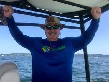 A man wearing a blue GreenPolly shirt on a boat