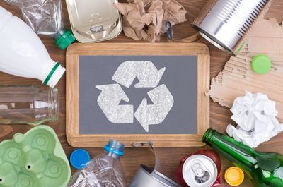 Recycle symbol on a chalkboard surrounded by recyclable goods