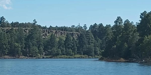 River with a forested rocky cliff in the background.