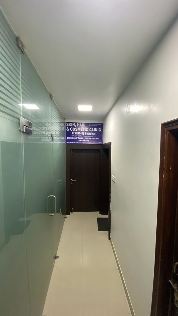 Narrow clinic hallway with glass door and blue sign.