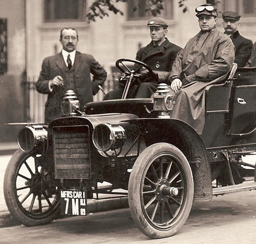 Vintage black and white photo of men with an early 20th-century automobile.