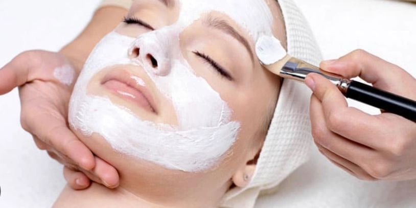 A woman relaxing while receiving a white facial mask treatment.