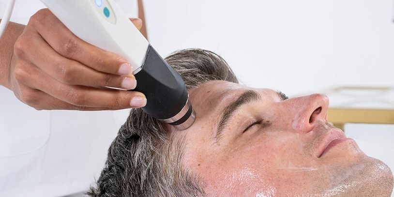 Man receiving a facial skin treatment with a handheld device.