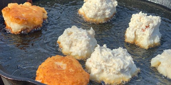 CLEGR FARMS- a cast iron frying pan with bannock wrapped hot dogs frying in oil