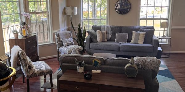 Cozy living room with gray sofas and floral chairs.