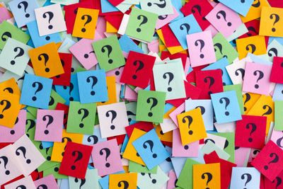 Colorful sticky notes with black question marks scattered randomly.