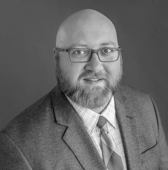 Professional man with glasses and a beard wearing a suit and tie.