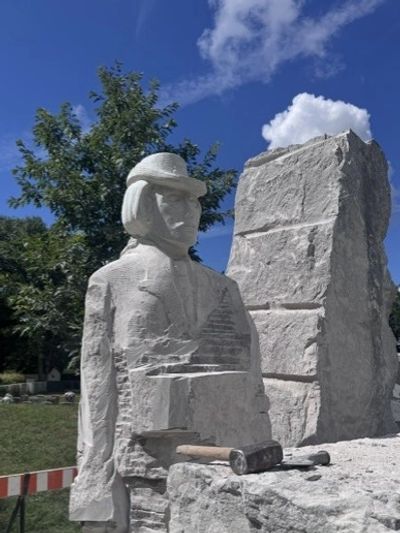 Statue en pierre d'un sculpteur avec marteau.