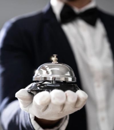 A butler in white gloves holding a service bell.